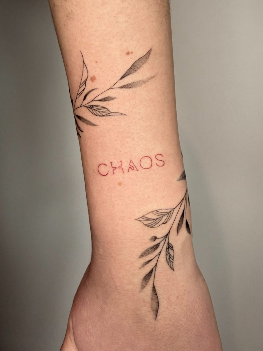 Tattoo auf dem Handgelenk mit dem Wort "CHAOS" und Pflanzen ums Handgelenk – Ink Shell aus dem Studio Rabauke Tattoo and Arts in Neu-Ulm