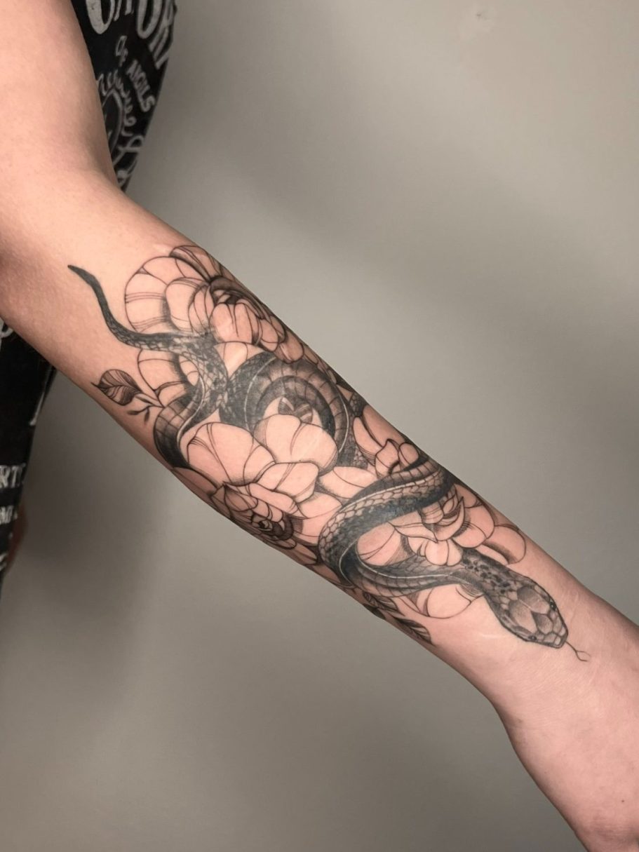 Schwarze Schlange mit floralen Fineline Elementen auf dem Unterarm tätowiert – Ink Shell, Neu-Ulm