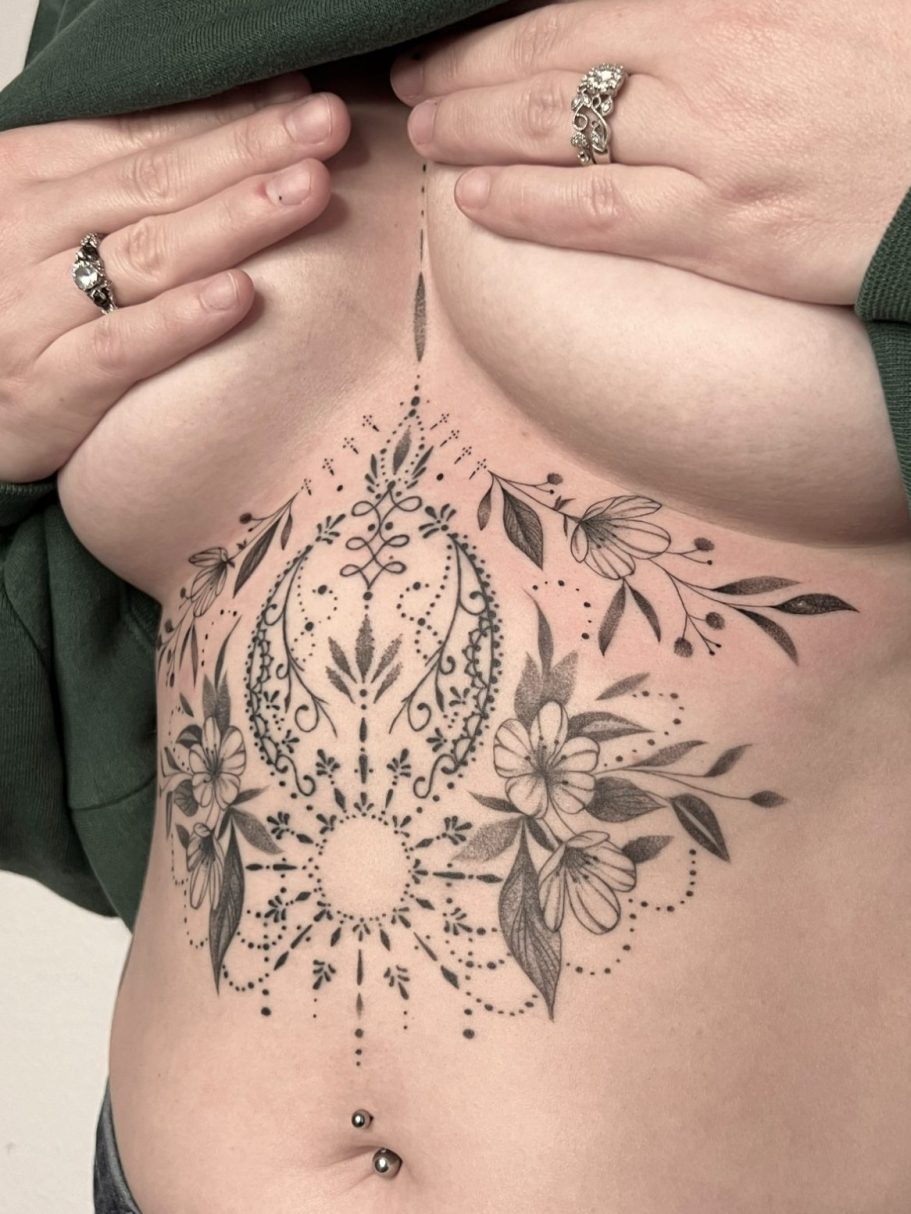 Underboob Tattoo auf dem Bauch einer Frau mit floralen Motiven und geometrischen Formen in Fineline – Ink Shell, Neu-Ulm